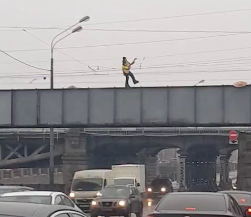 В Петербурге кто-то неведомый зачем-то катается по парапету моста на роликах и с гитарой 