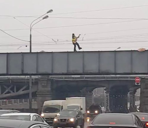 В Петербурге кто-то неведомый зачем-то катается по парапету моста на роликах и с гитарой
